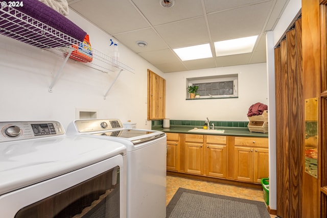 washroom with cabinets, washing machine and dryer, and sink