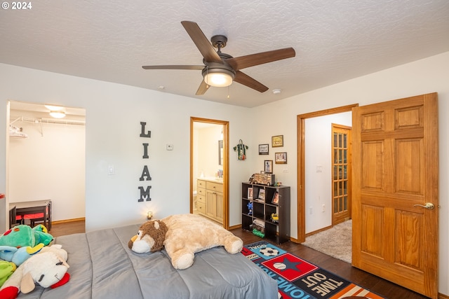 bedroom with dark wood-type flooring, ensuite bathroom, ceiling fan, a textured ceiling, and a closet