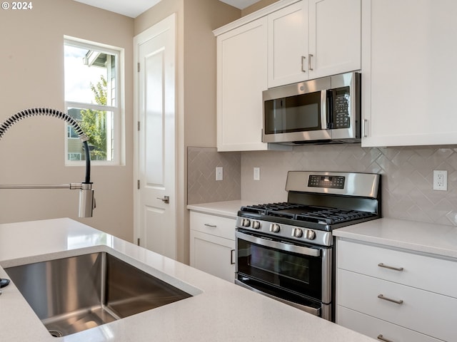 kitchen with sink, white cabinetry, stainless steel appliances, and tasteful backsplash