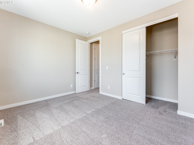 unfurnished bedroom with light colored carpet and a closet