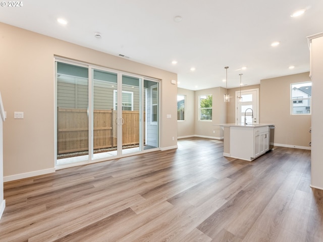 unfurnished living room with sink and light wood-type flooring