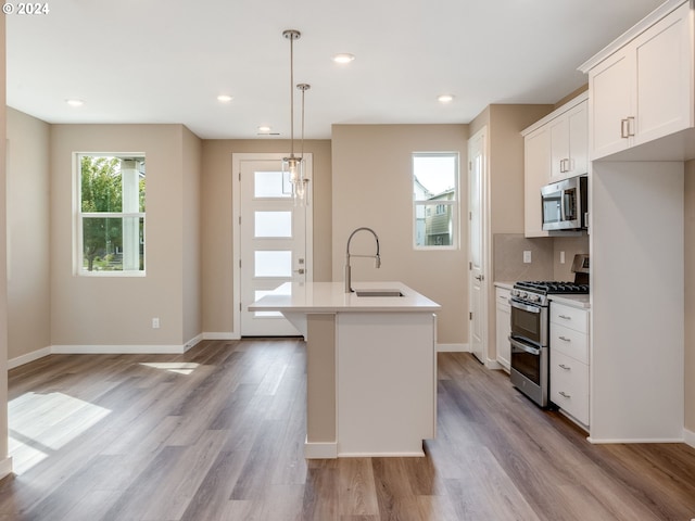 kitchen with stainless steel appliances, white cabinetry, a kitchen island with sink, and sink