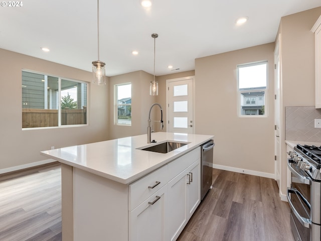 kitchen with pendant lighting, a center island with sink, sink, tasteful backsplash, and stainless steel appliances