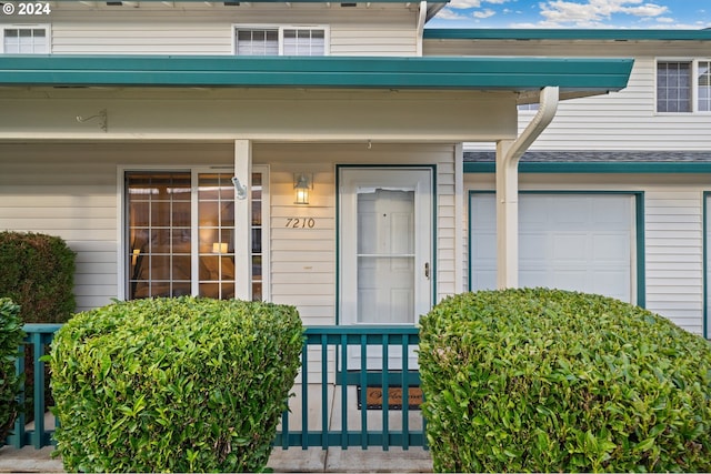 view of exterior entry featuring a porch and a garage