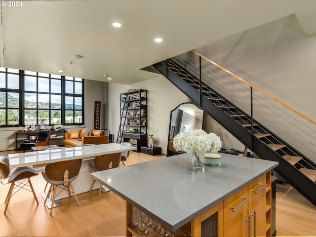 kitchen featuring light wood-style flooring, modern cabinets, a kitchen island, brown cabinets, and open floor plan