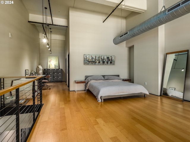 bedroom featuring light hardwood / wood-style flooring and a towering ceiling