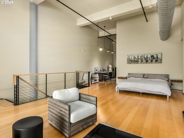 bedroom featuring hardwood / wood-style flooring, beam ceiling, and a towering ceiling