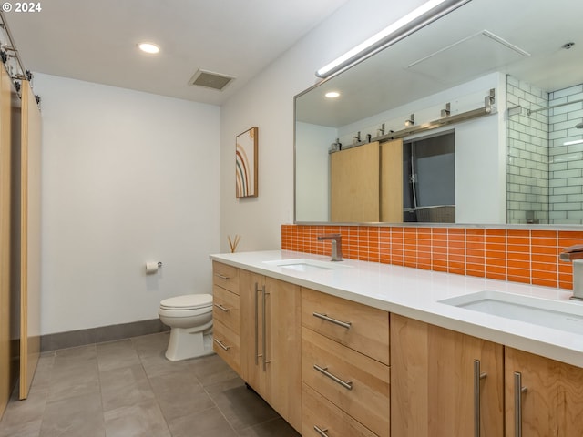 full bathroom featuring double vanity, backsplash, a sink, and toilet