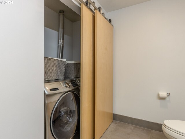 laundry room with light tile patterned floors, washer / dryer, and a barn door