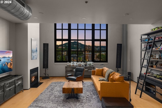 living area featuring light wood-type flooring and a fireplace with flush hearth