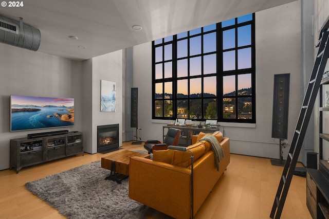 living room with light hardwood / wood-style floors and a towering ceiling