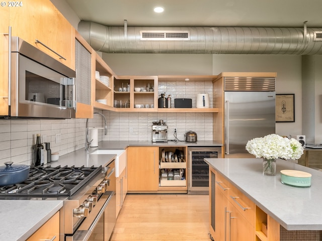 kitchen with light wood-type flooring, wine cooler, tasteful backsplash, and high end appliances