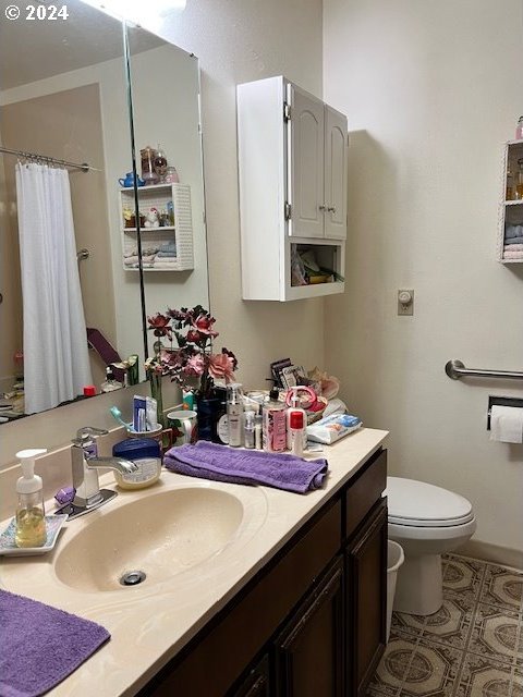 bathroom with toilet, walk in shower, and vanity