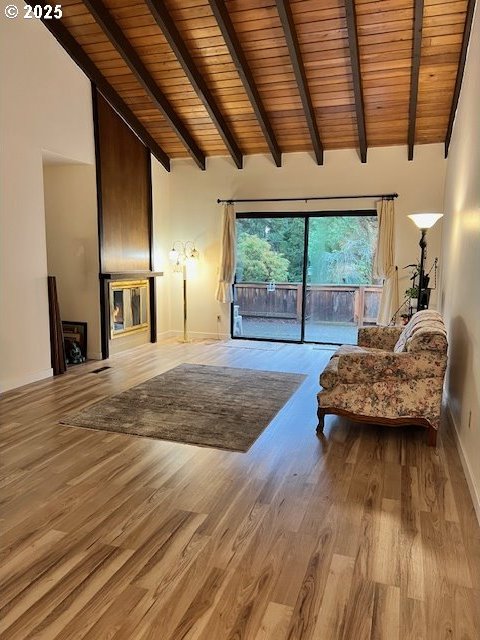 living room with beamed ceiling, high vaulted ceiling, light hardwood / wood-style floors, and wood ceiling