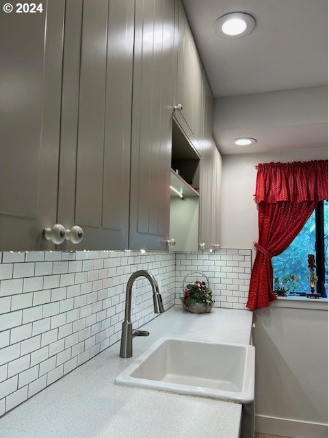 kitchen with gray cabinets, backsplash, and sink