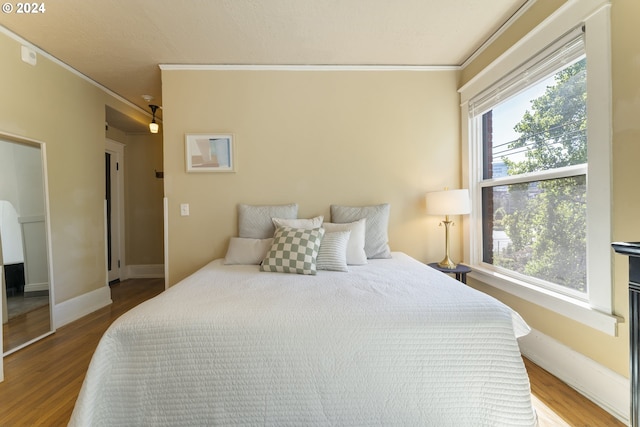 bedroom with crown molding, multiple windows, and hardwood / wood-style flooring