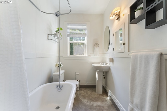 bathroom featuring a tub, concrete flooring, toilet, and sink