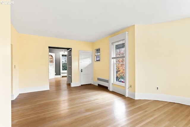 empty room featuring radiator and light hardwood / wood-style flooring