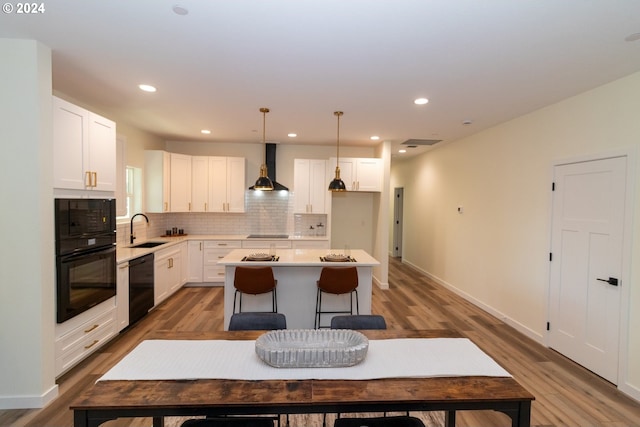 6018 Little Woahink Dr, Florence, OR 97439 - kitchen with black appliances, a kitchen island, wood finished floors, wall chimney exhaust hood, and recessed lighting