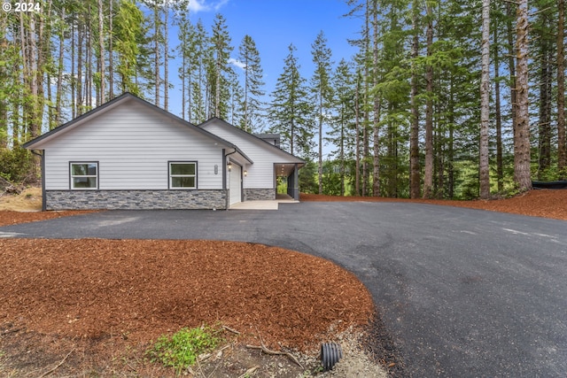 6018 Little Woahink Dr, Florence, OR 97439 - view of side of property with asphalt driveway, stone siding, and a garage