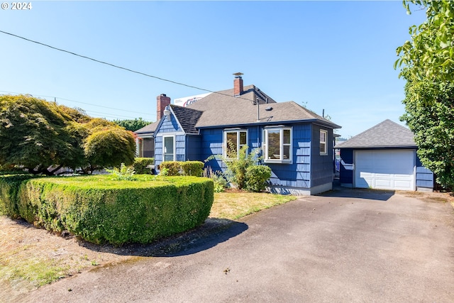 bungalow-style house featuring a garage and an outbuilding