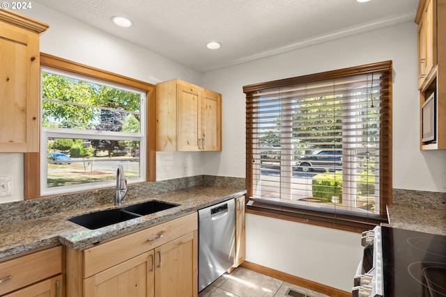 kitchen with light brown cabinetry, light tile patterned floors, stone counters, appliances with stainless steel finishes, and sink