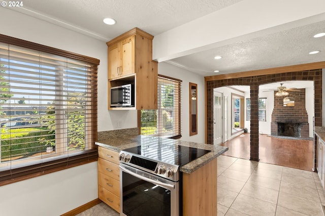 kitchen with a textured ceiling, light hardwood / wood-style flooring, ceiling fan, and appliances with stainless steel finishes