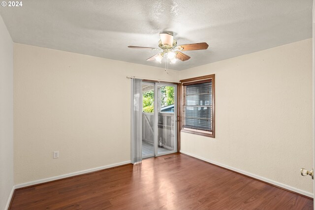 empty room with ceiling fan, dark hardwood / wood-style flooring, and a textured ceiling