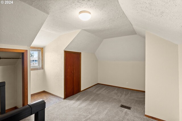 bonus room with light carpet, a textured ceiling, and lofted ceiling