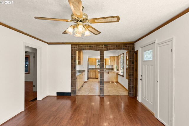 foyer entrance featuring ceiling fan, crown molding, a textured ceiling, and light hardwood / wood-style flooring