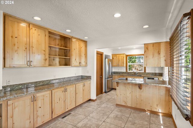 kitchen featuring stainless steel fridge, light brown cabinets, stone countertops, and sink