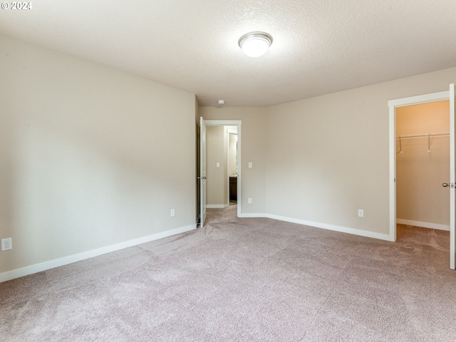 empty room with light colored carpet and a textured ceiling