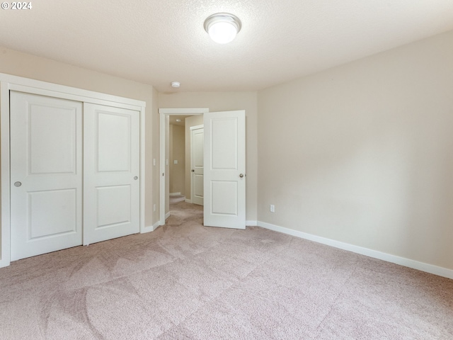 unfurnished bedroom featuring a closet, light colored carpet, and a textured ceiling