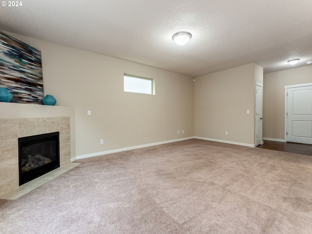 unfurnished living room featuring carpet flooring, a textured ceiling, and a tiled fireplace