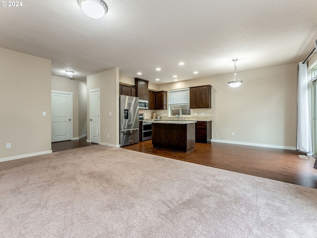 kitchen with a center island, dark hardwood / wood-style floors, pendant lighting, a textured ceiling, and appliances with stainless steel finishes