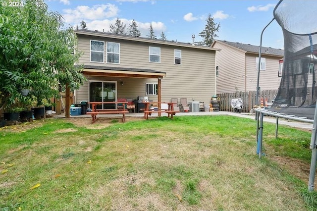 rear view of property with a trampoline, a patio, a yard, and cooling unit