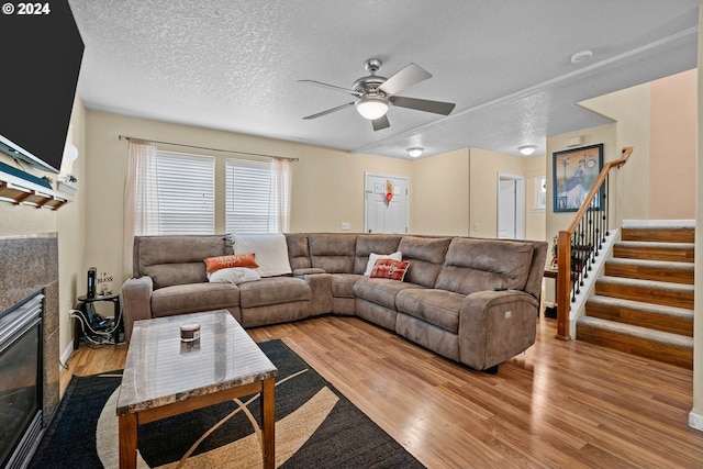 living room featuring ceiling fan, a textured ceiling, and light wood-type flooring