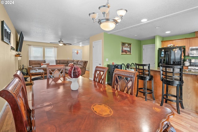 dining area featuring ceiling fan with notable chandelier, light hardwood / wood-style floors, and a textured ceiling