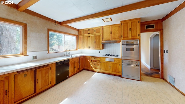 kitchen featuring oven, beam ceiling, dishwasher, and light hardwood / wood-style flooring