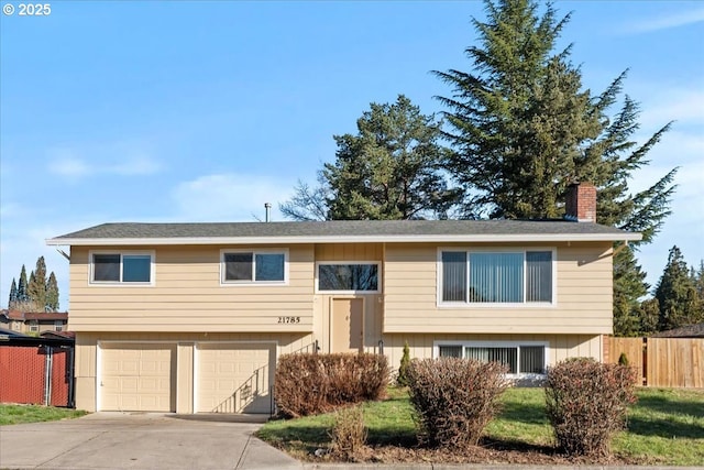21785 SW York St, Beaverton, OR 97003 - bi-level home featuring a chimney, an attached garage, and concrete driveway