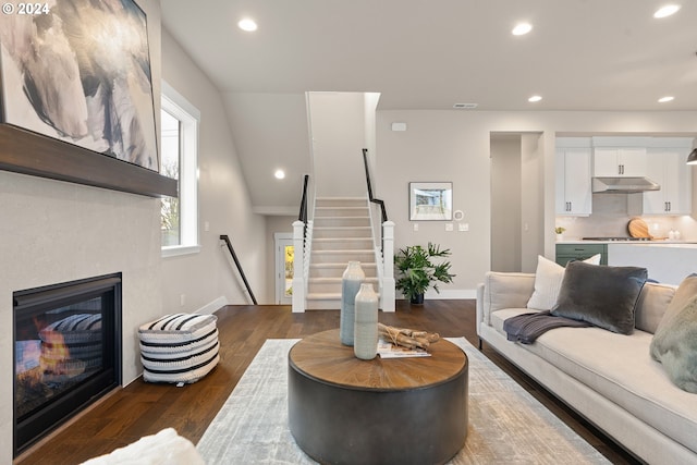 living room featuring recessed lighting, visible vents, stairway, dark wood-type flooring, and a glass covered fireplace