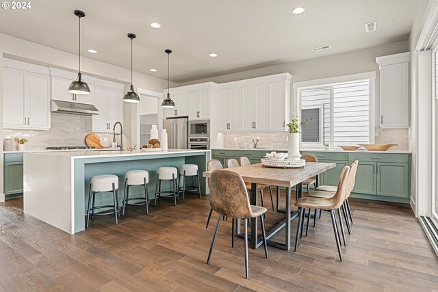 kitchen with hardwood / wood-style floors, stainless steel appliances, and a kitchen island with sink