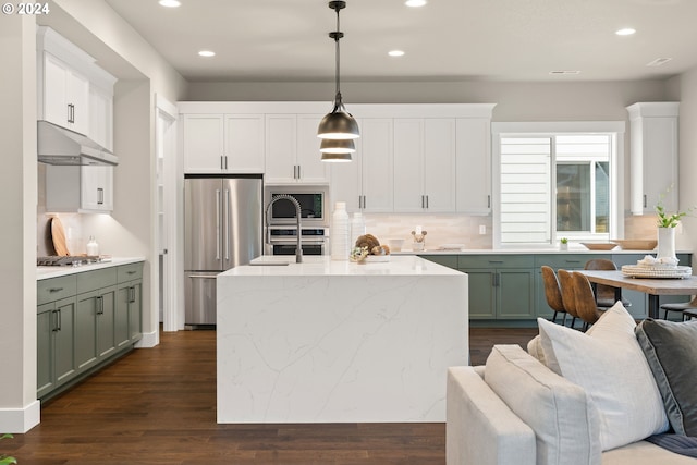 kitchen with under cabinet range hood, appliances with stainless steel finishes, pendant lighting, and green cabinetry