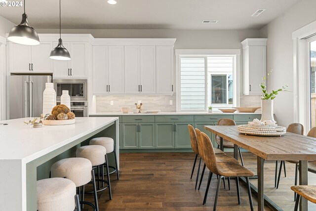 kitchen with decorative backsplash, stainless steel appliances, decorative light fixtures, dark hardwood / wood-style floors, and green cabinets