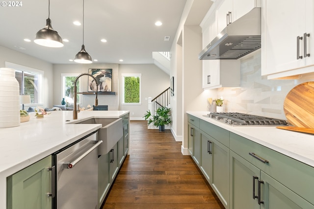 kitchen featuring white cabinetry, hanging light fixtures, dark wood-type flooring, backsplash, and appliances with stainless steel finishes