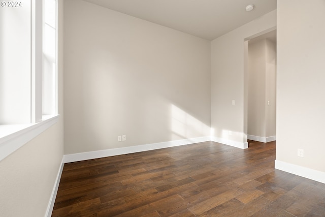 unfurnished room with dark wood-type flooring and baseboards