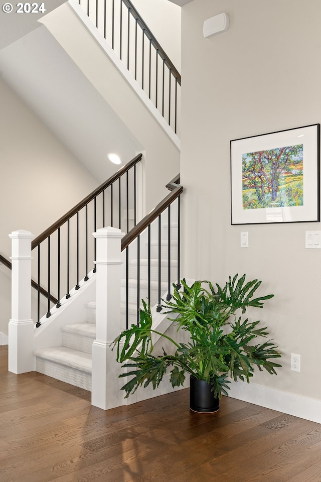 stairway with hardwood / wood-style floors and a high ceiling