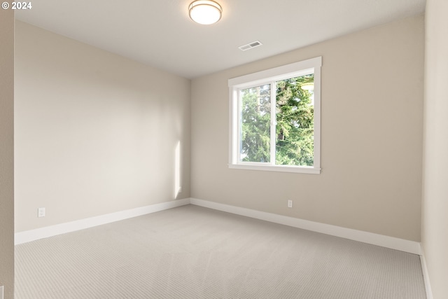 carpeted spare room with visible vents and baseboards