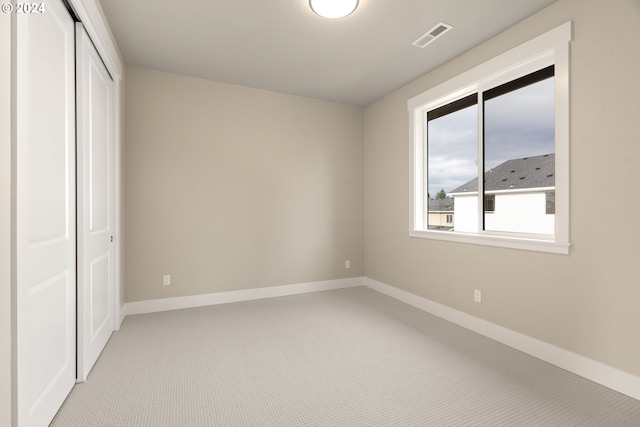 unfurnished bedroom with baseboards, a closet, visible vents, and light colored carpet