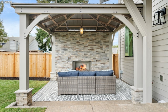 view of patio / terrace featuring an outdoor living space with a fireplace, fence, and a gazebo